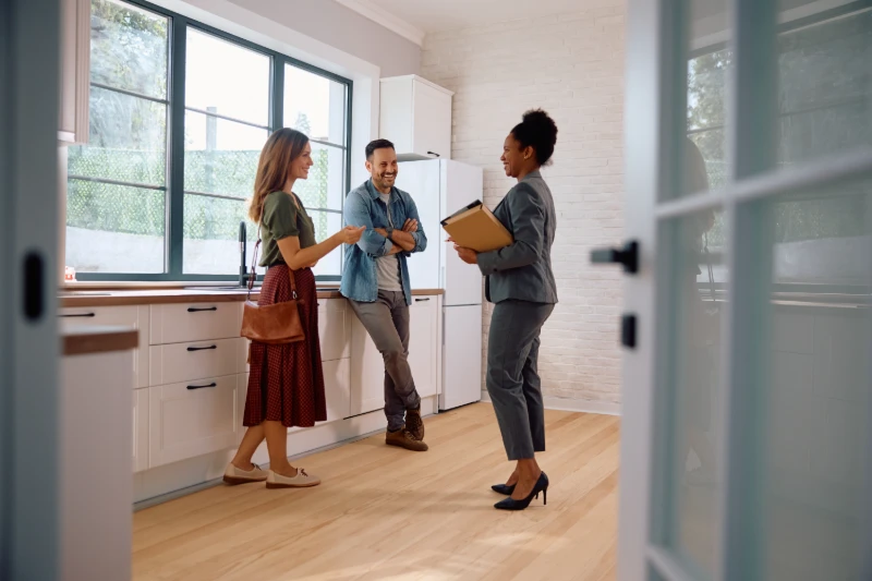 Happy couple talking with real estate agent while buying new home
